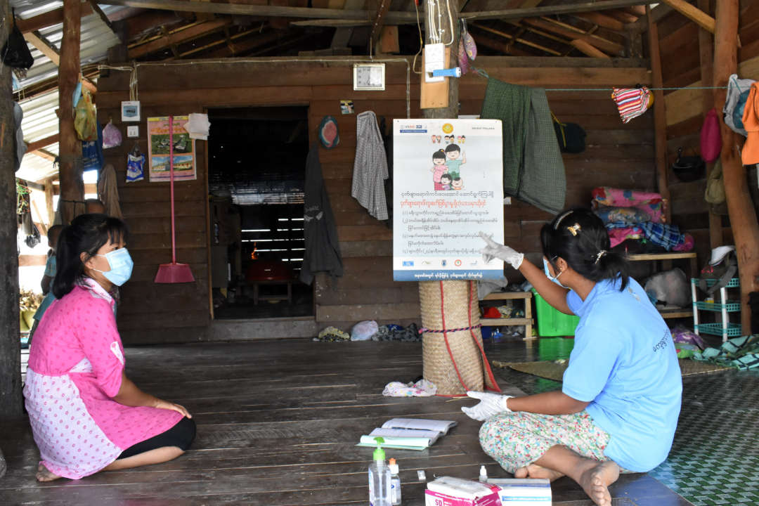 A community health worker reviews a malaria prevention educational poster. Photo credit: URC